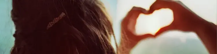 una mujer con sus manos en forma de corazon